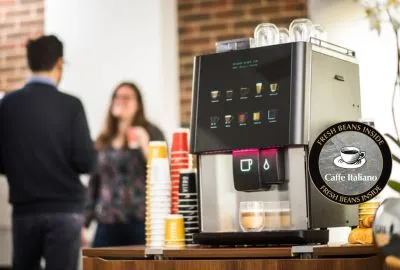 Admiral Vending - Commercial Coffe Machines - Image of coffee machine in office with man and woman standing to side enjoying a cup of coffee